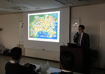 スライドを使いながら講演している写真です